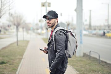 man wearing black leather jacket holding smartphone